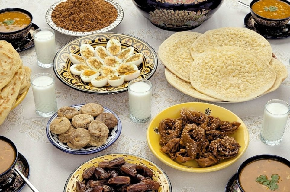 A table is set with a variety of Moroccan foods that are traditionally served in Ramadan. Shown are eggs, dried fruits,beghrir, msemen, harira and sellou.
