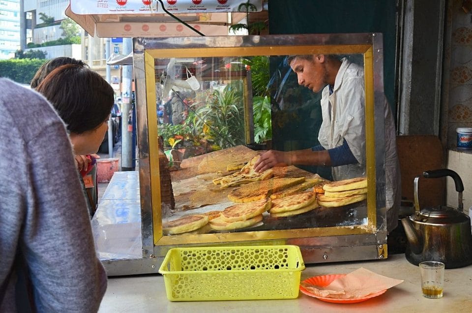 A Moroccan vendor serves tourists some of the stove top breads he sells.